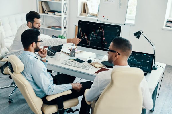 Cooperation in action. Group of young modern men in formalwear working using computers while sitting in the office